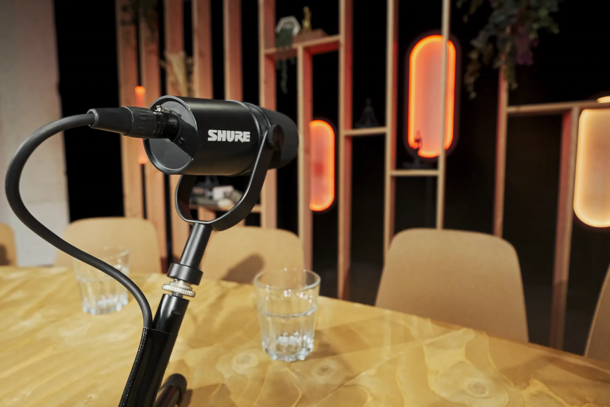 Micro broadcast Shure sur la table du podcast, décor éclairé en arrière-plan